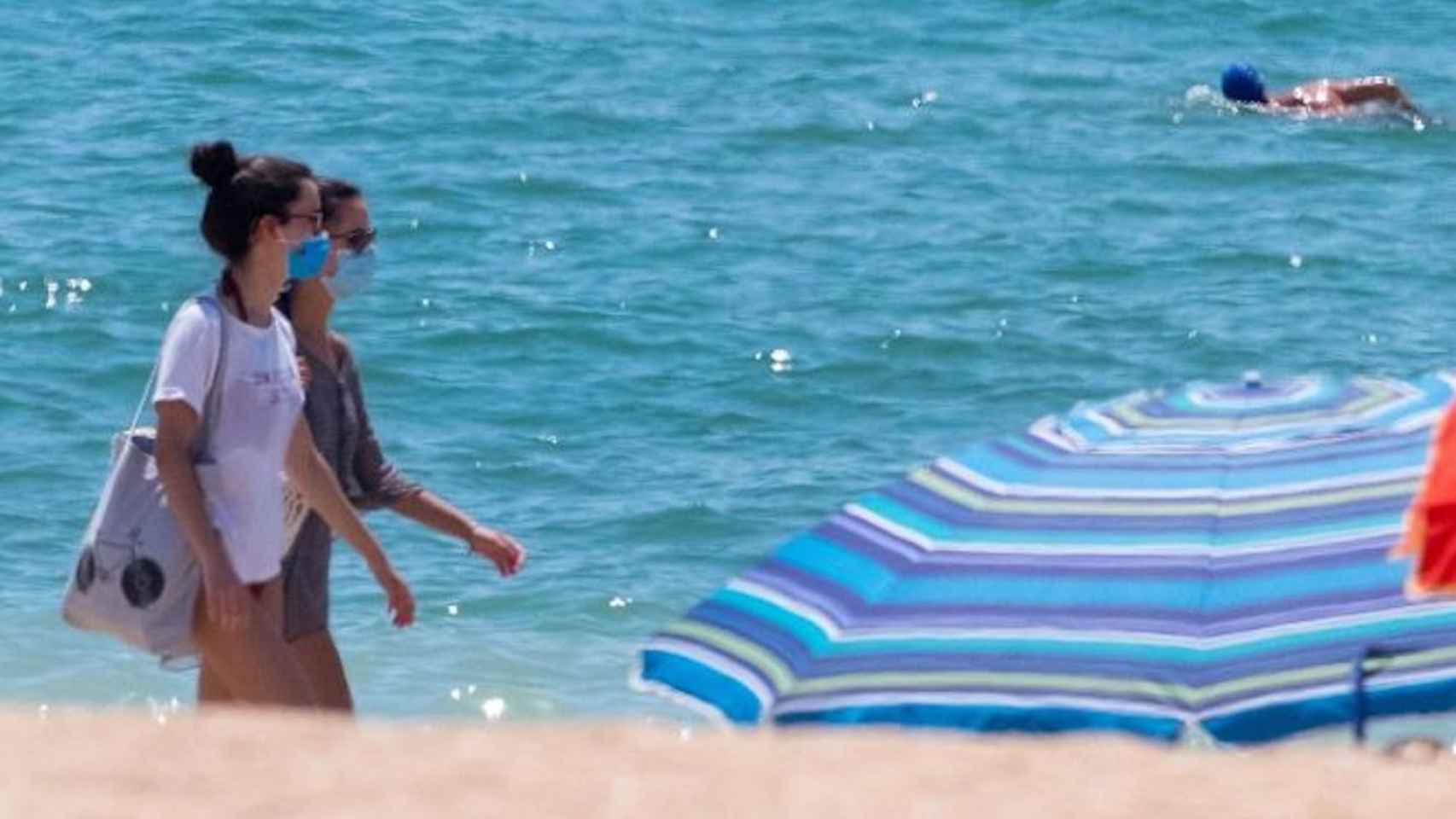 Dos chicas en la playa y con mascarilla en un día de calor / EFE