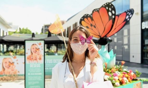 Una joven posa frente a la mariposa gigante de los artistas falleros y las flores de Mariscal / CEDIDA