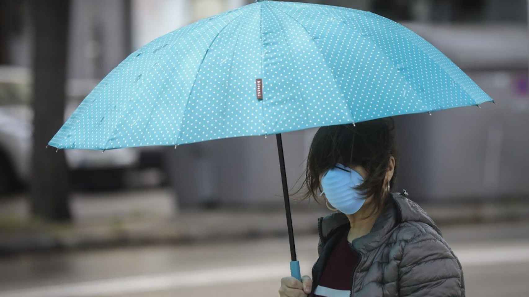 Una chica con paraguas y mascarilla en un día de lluvia / EUROPA PRESS