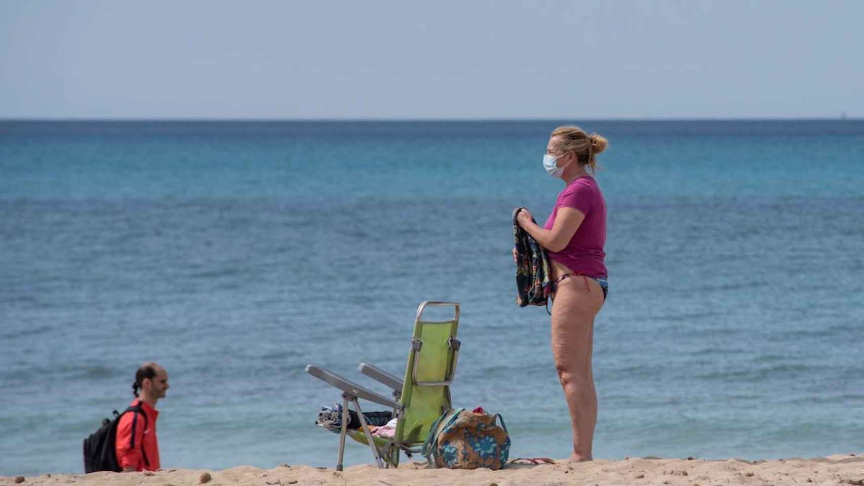 Una mujer en la playa con mascarilla / EFE