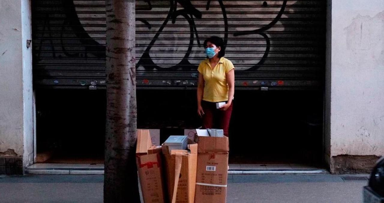 Una vecina en Sant Andreu junto a unos paquetes de cartón de la recogida de basura / METRÓPOLI - PABLO MIRANZO