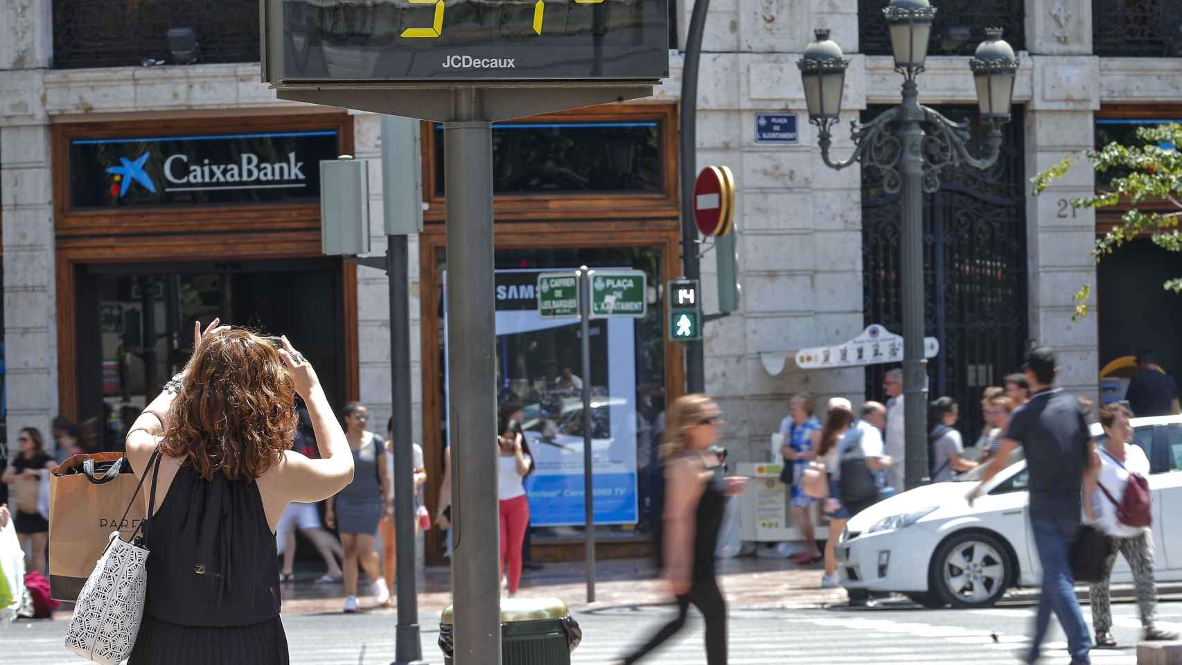 Una mujer toma una fotografía de un termómetro urbano / EFE