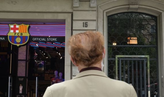 Un hombre observa el portal de un edificio del paseo de Gràcia en el que cuelga el cartel de se vende / PABLO MIRANZO