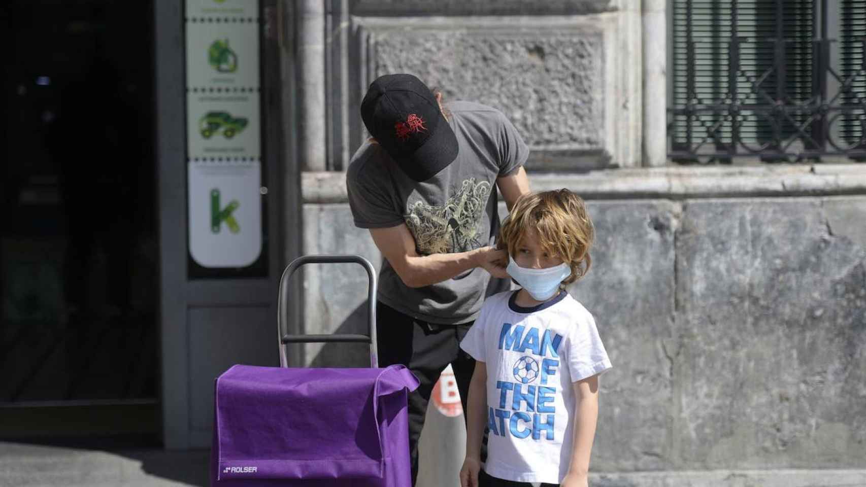 Un padre coloca la mascarilla a su hijo / EFE