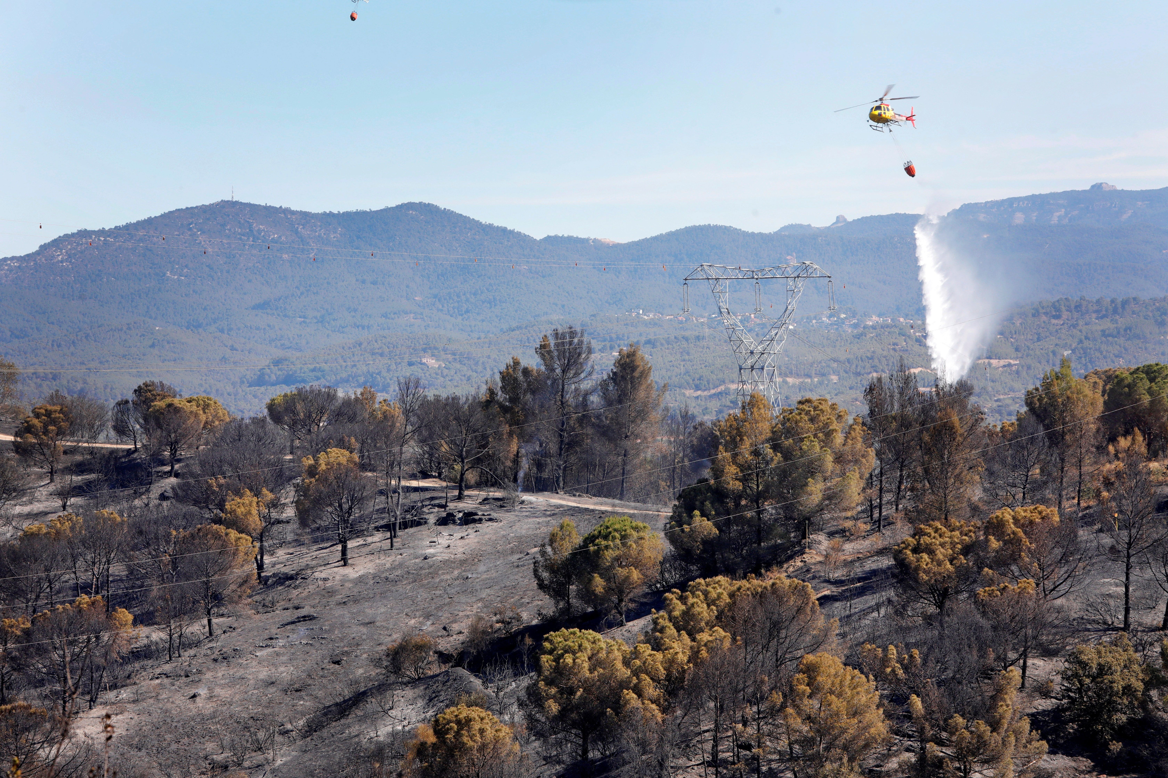 Un hidroavión trabaja cerca de la urbanización de Can Sunyer. El incendio que afecta a los términos de Castellví de Rosanes y Martorell, en Barcelona, continúa activo tras calcinar unas 200 hectáreas, en su mayoría de terreno forestal, en el peor de estos