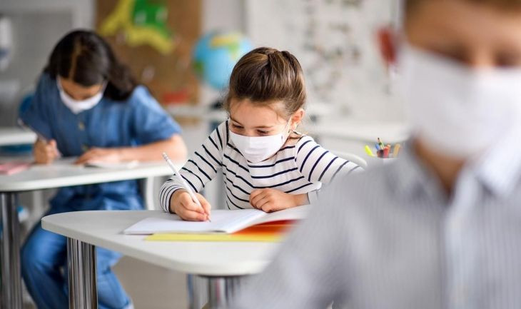 Tres estudiantes es una clase protegidos con una mascarilla