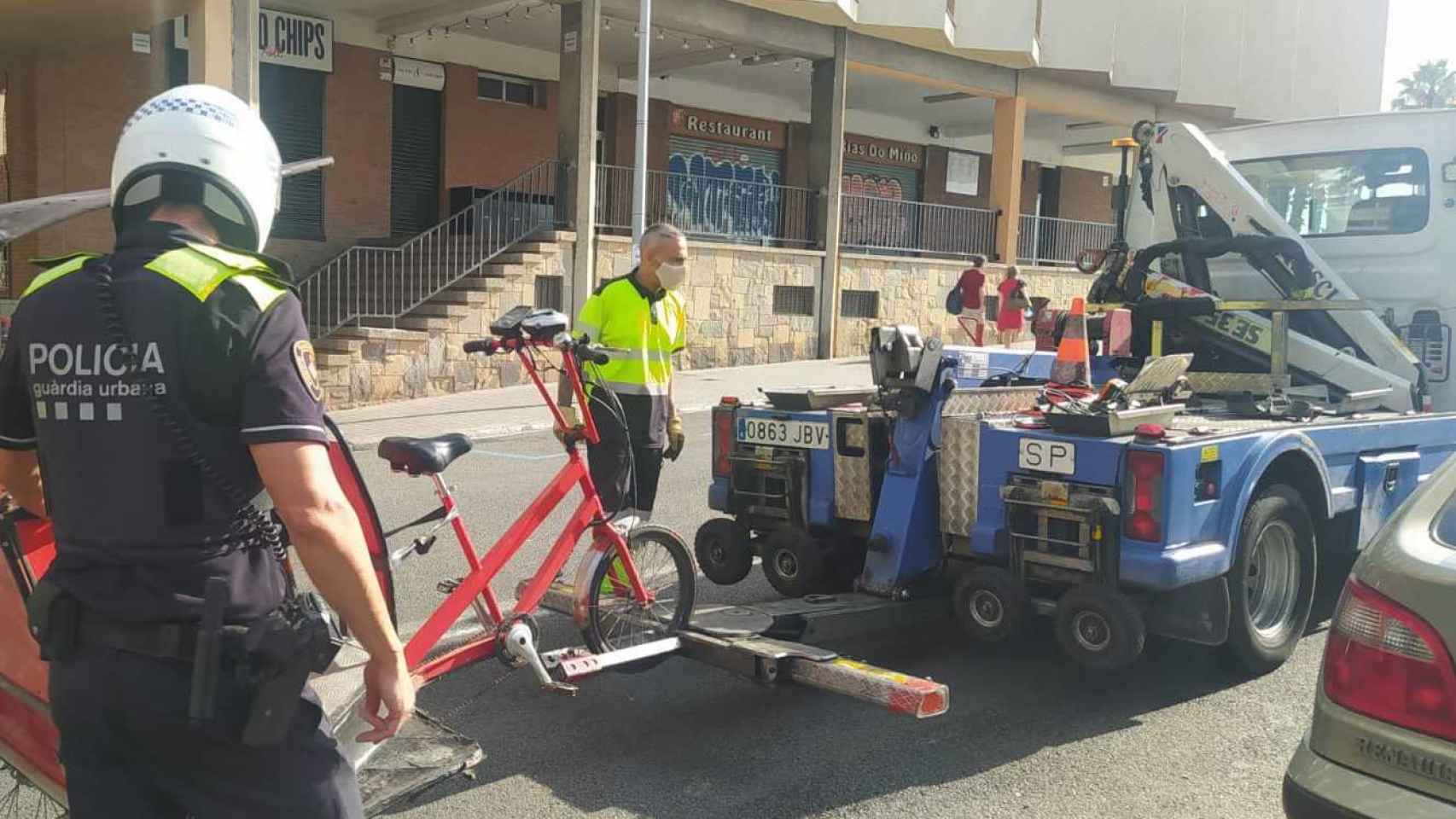 Una grúa municipal se lleva un bicitaxi ante un agente de la Guardia Urbana / TWITTER GUARDIA URBANA