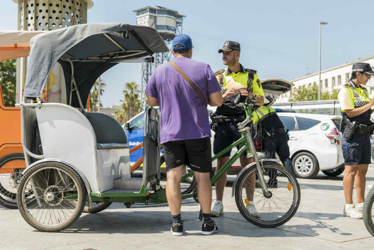 Unos guardias urbanos multan al conductor de un bicitaxi / AYUNTAMIENTO BARCELONA