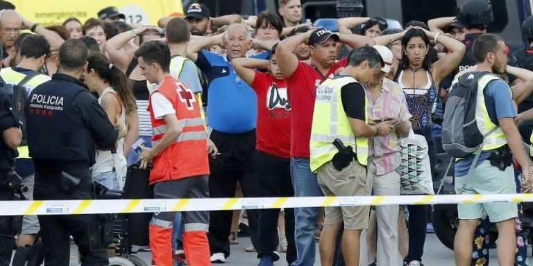 Un grupo de gente con los brazos en alto ante el despliegue policial / EFE