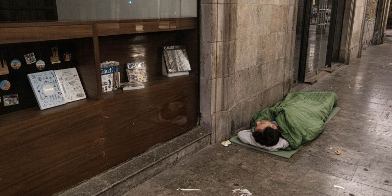 Una persona sin hogar durmiendo en una calle del centro de Barcelona / PABLO MIRANZO - MA