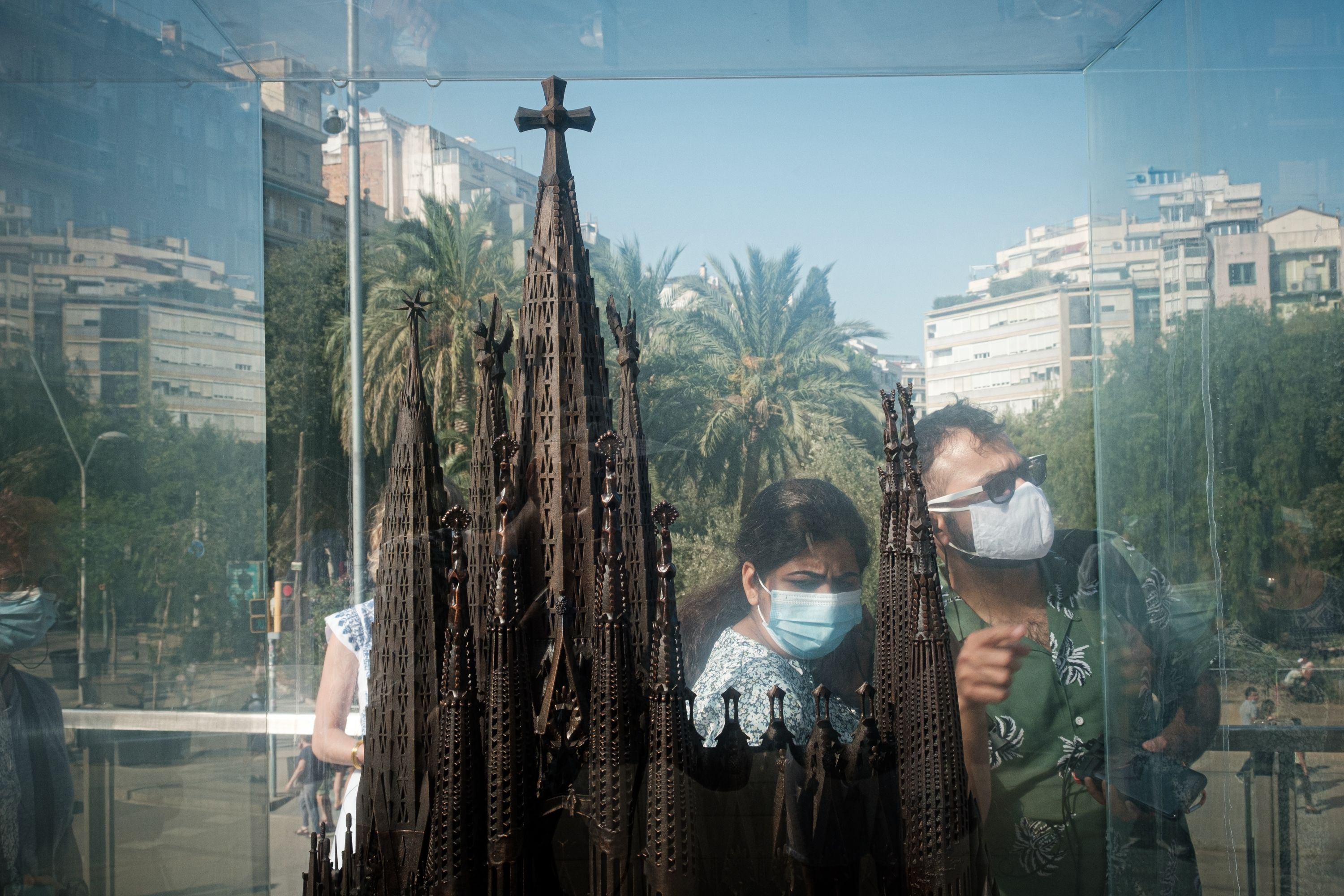 Dos turistas con mascarilla se reflejan en uno de los expositores de las maquetas de la Sagrada Família / PABLO MIRANZO - MA