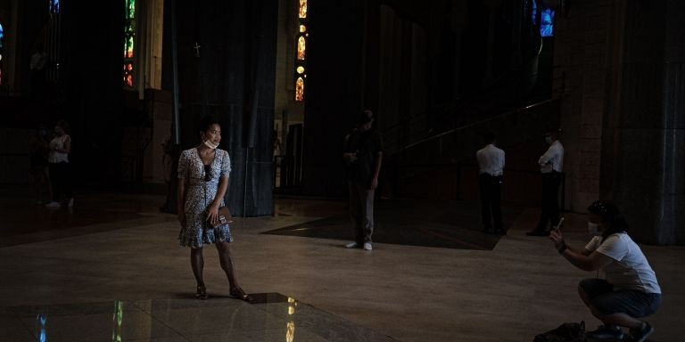 Una turista se baja la mascarilla para posar para una foto en el interior de la Sagrada Família durante las restricciones por covid / PABLO MIRANZO - MA