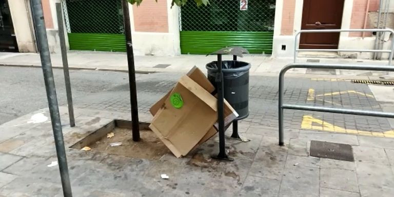Una caja de cartón junto a una papelera en una calle de Sarrià / METRÓPOLI - JORDI SUBIRANA