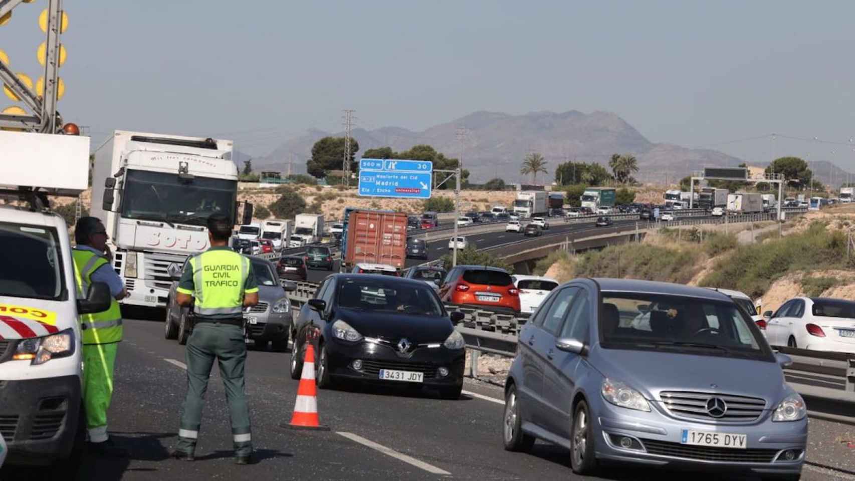 Imagen de archivo de la autovía con grandes retenciones y un agente dirigiendo el tráfico