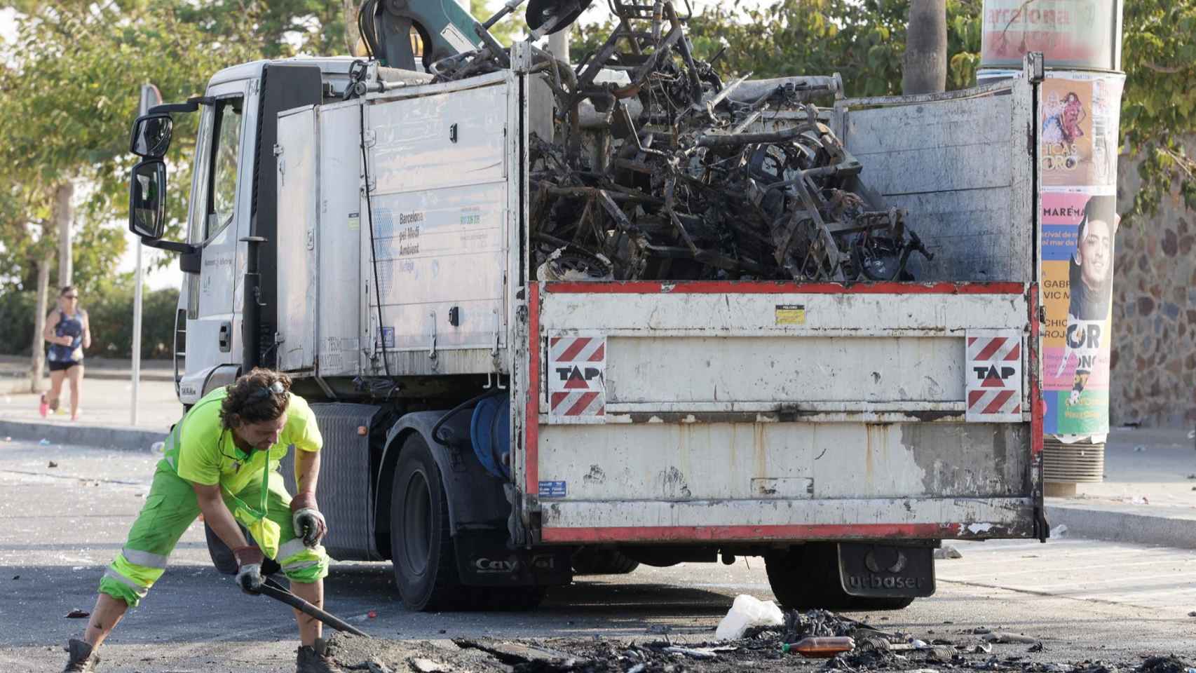 El servicio de limpieza recoge restos de motos calcinadas durante el tercer macrobotellón de la Mercè / EFE