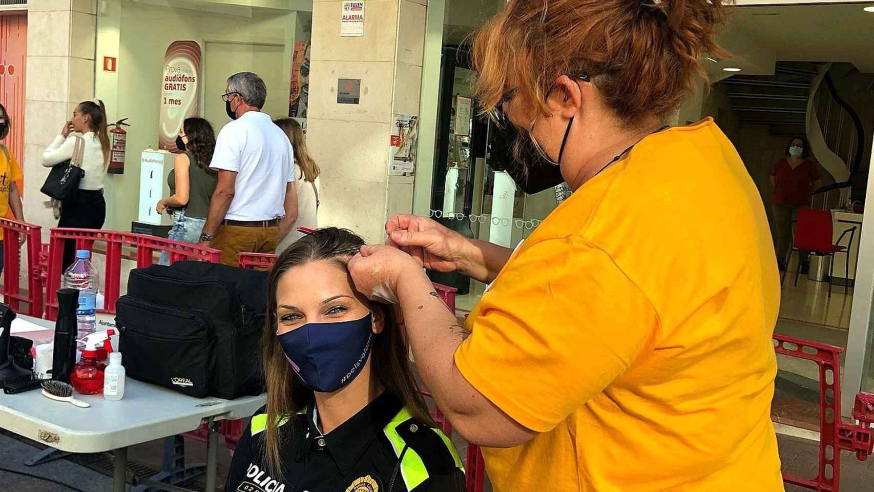 Una agente en manos de una estilista durante la celebración de la iniciativa solidaria / POLICÍA MUNICIPAL DE TERRASSA