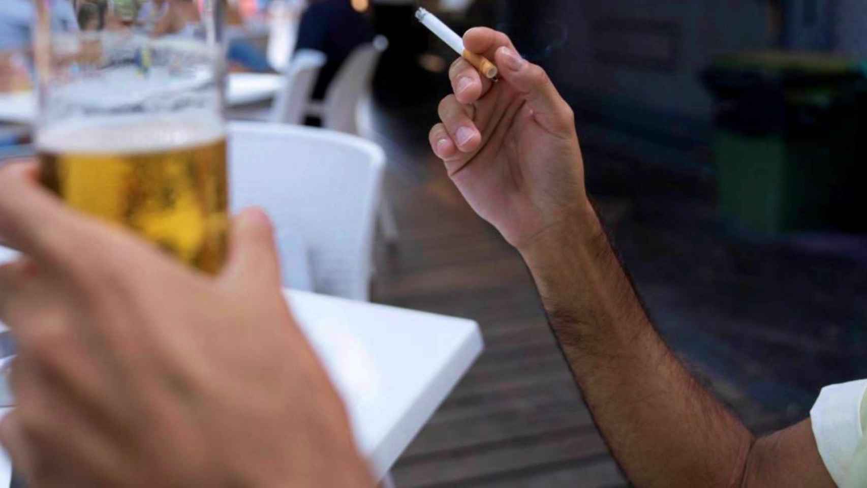 Un cliente en una terraza con un cigarrillo en la mano