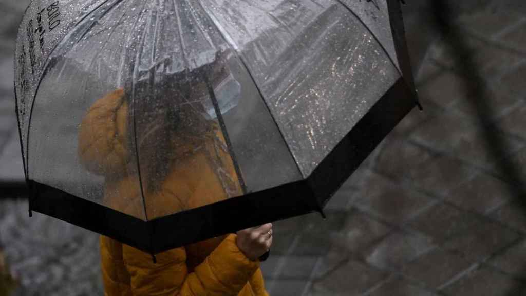 Una mujer con paraguas y mascarilla en un día de lluvia / EUROPA PRESS