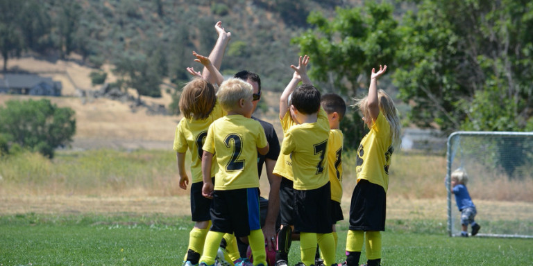 Un entrenador habla con niños pequeños durante la práctica deportiva / PIXABAY