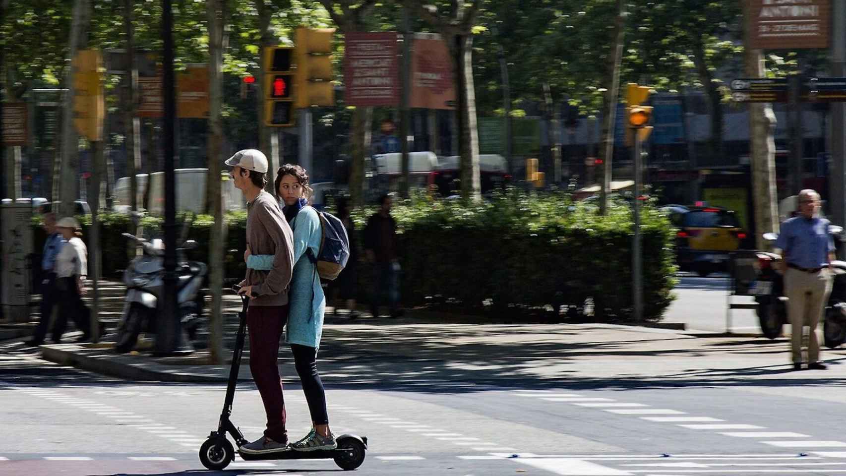 Dos usuarios en un patinete circulan por Barcelona