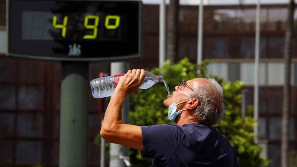 Un hombre bebe agua en plena ola de calor