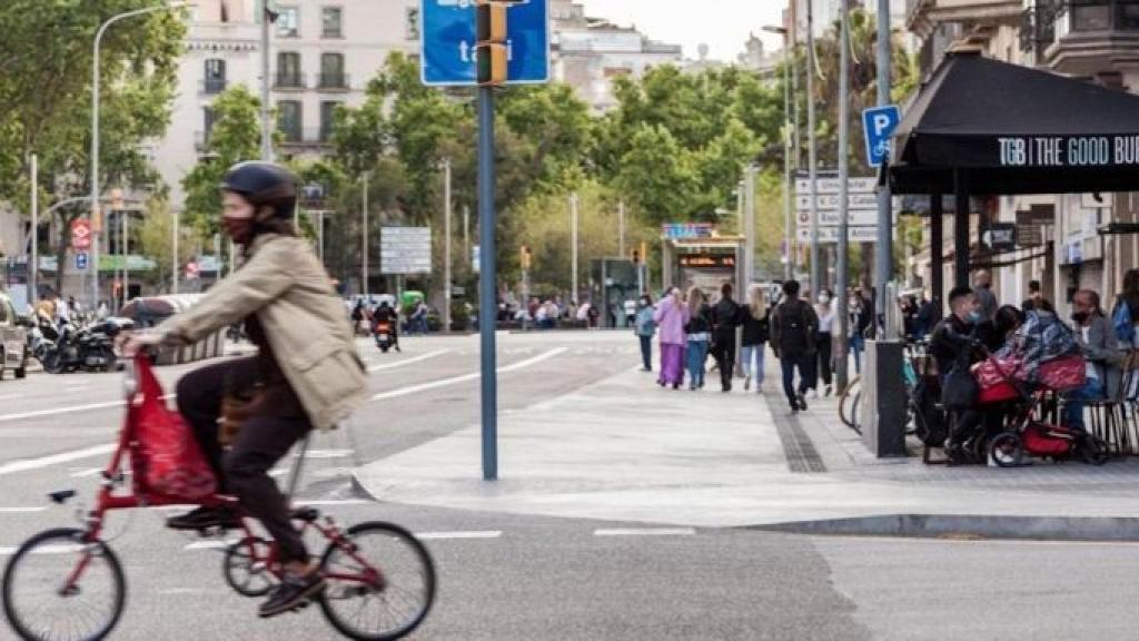 Una bicicleta pasa por delante de la terraza de un bar en Barcelona