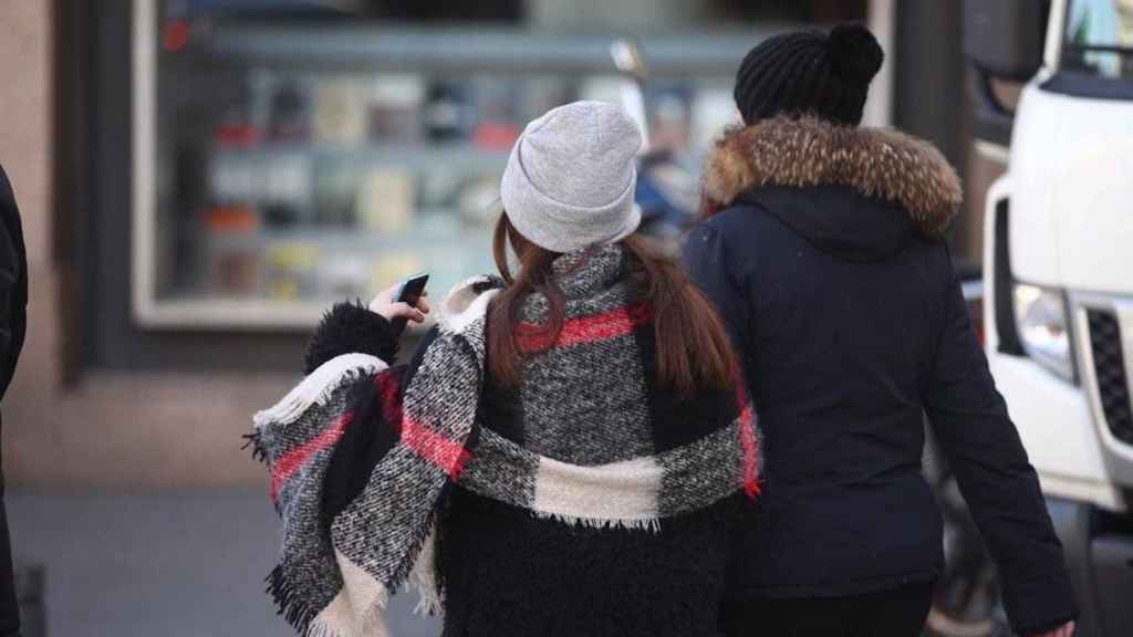 Dos mujeres pasean por la calle muy abrigadas en plena ola de frío en Barcelona