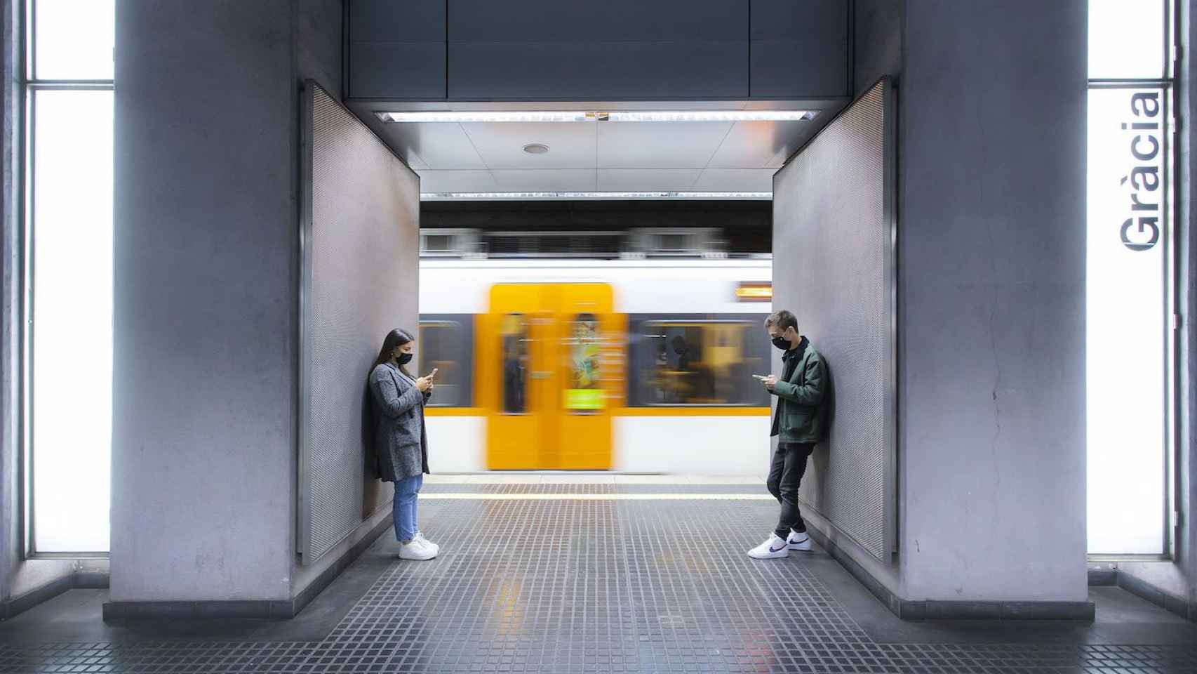 Dos personas esperan en el andén de la parada de Gràcia de Ferrocarrils de la Generalitat de Catalunya