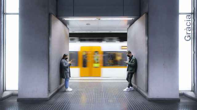 Dos personas esperan en el andén de la parada de Gràcia de Ferrocarrils de la Generalitat de Catalunya / FGC