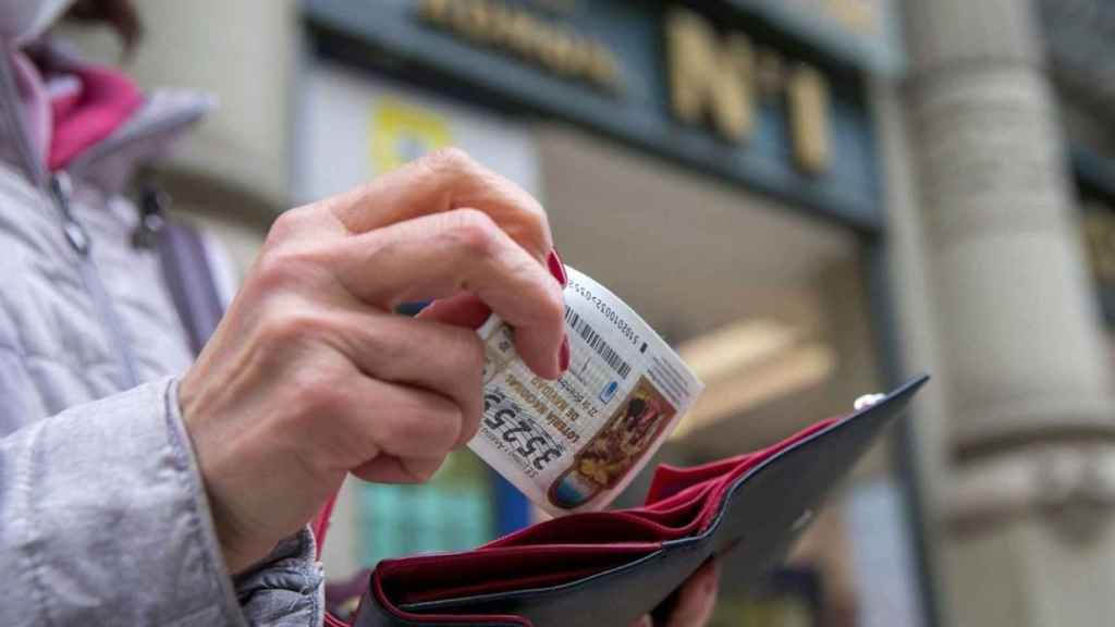 Una mujer guarda un décimo de la lotería de Navidad que acaba de comprar