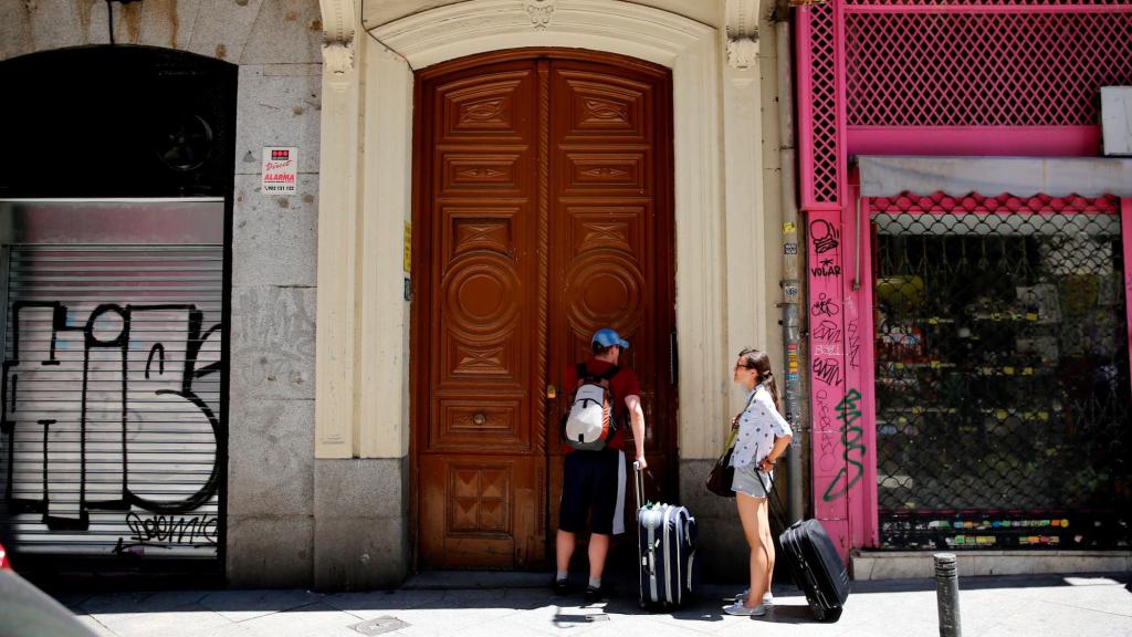 Dos turistas esperan frente a un apartamento turístico en Barcelona