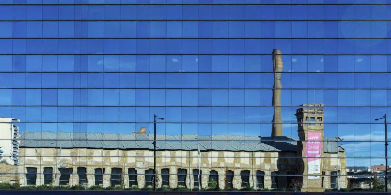 Reflejo de Can Batlló en una fachada de Barcelona / INMA SANTOS