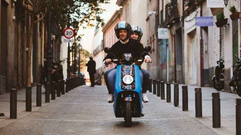 Una pareja haciendo uso de una moto eléctrica compartida ('motosharing')