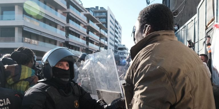 Un hombre y un policía discuten enfrente de la nave okupada en Badalona / PABLO MIRANZO - MA