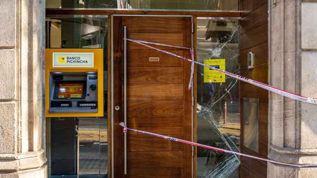 Una de las puertas de entrada al Banco Pichincha de Barcelona, precintada con una cinta da de Mossos y con cristales rotos / METRÓPOLI - LUIS MIGUEL AÑÓN
