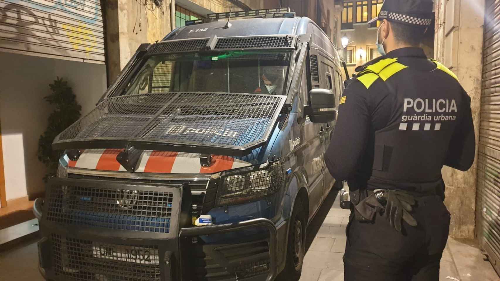 Un agente de la Guardia Urbana delante de una furgoneta de los Mossos / TWITTER MOSSOS