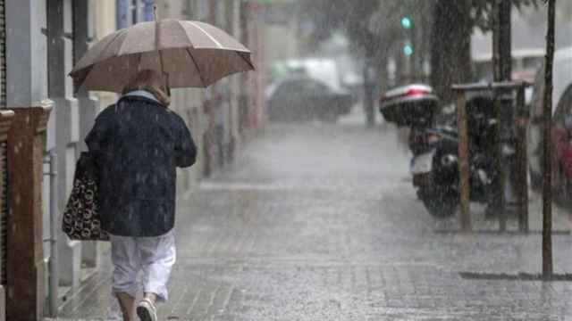 Una mujer se protege de la lluvia con un paraguas durante una alerta amarilla en Barcelona / EFE