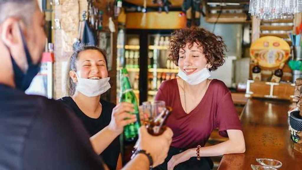 Amigos en un bar con la mascarilla bajada para tomar algo / ISTOCK