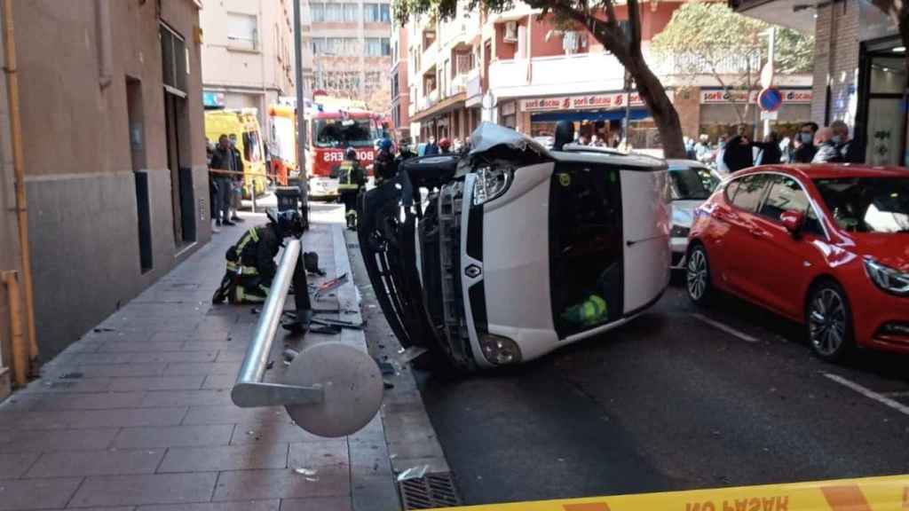 El coche volcado, en el Bon Pastor, con la farola destrozada al lado / CEDIDA