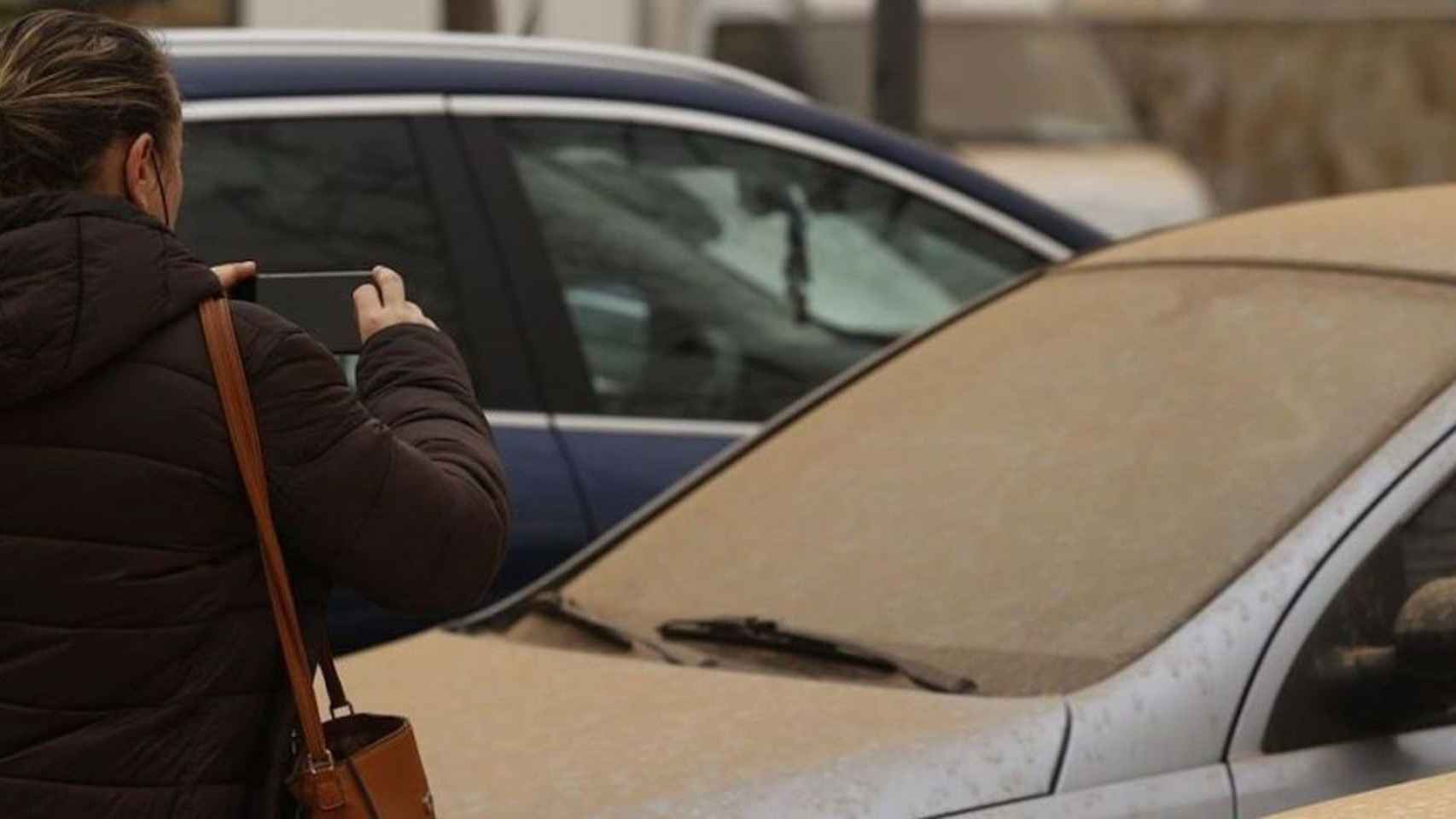 Una mujer fotografía su coche tras la lluvia de barro de la pasada semana / EFE