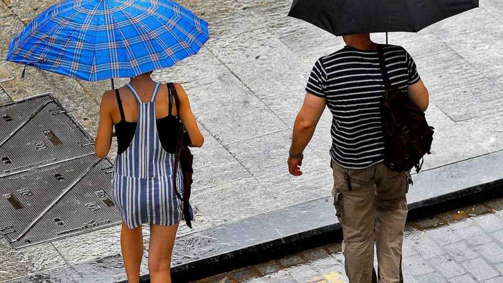 Dos personas se protegen de la lluvia de verano en Barcelona / EFE