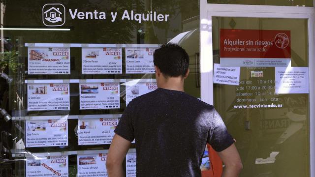Un hombre observa precios de vivienda de compra y alquiler en una inmobiliaria