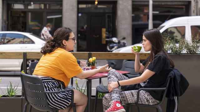 Dos jóvenes toman café en una terraza en Barcelona