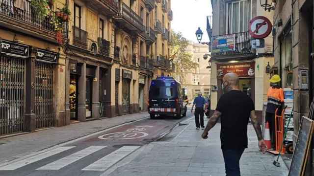 Un furgón policial circula en la calle de l'Hospital, donde han ocurrido los hechos, en el Raval / GUILLEM ANDRÉS