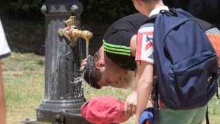 Un joven se moja la cabeza en Barcelona durante una ola de calor / EFE