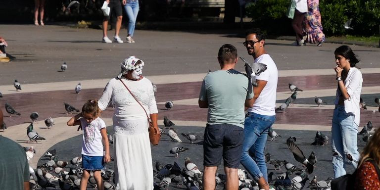 Una de las payasas junto a una niña y turistas en la plaza de Cataluña, donde también actúan / METRÓPOLI