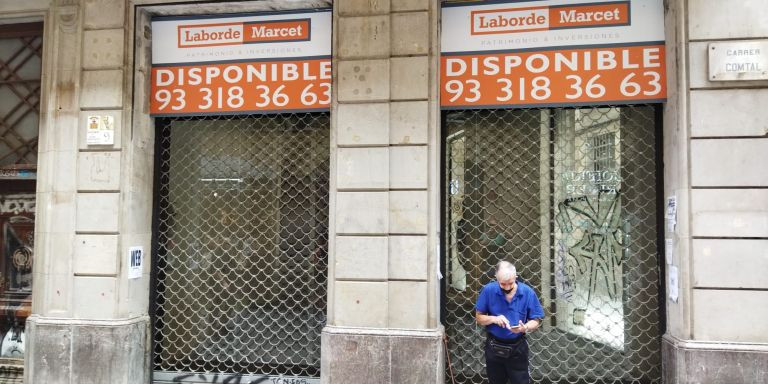 Un establecimiento de la calle Comtal con un cartel de una inmobiliaria / METRÓPOLI - JORDI SUBIRANA