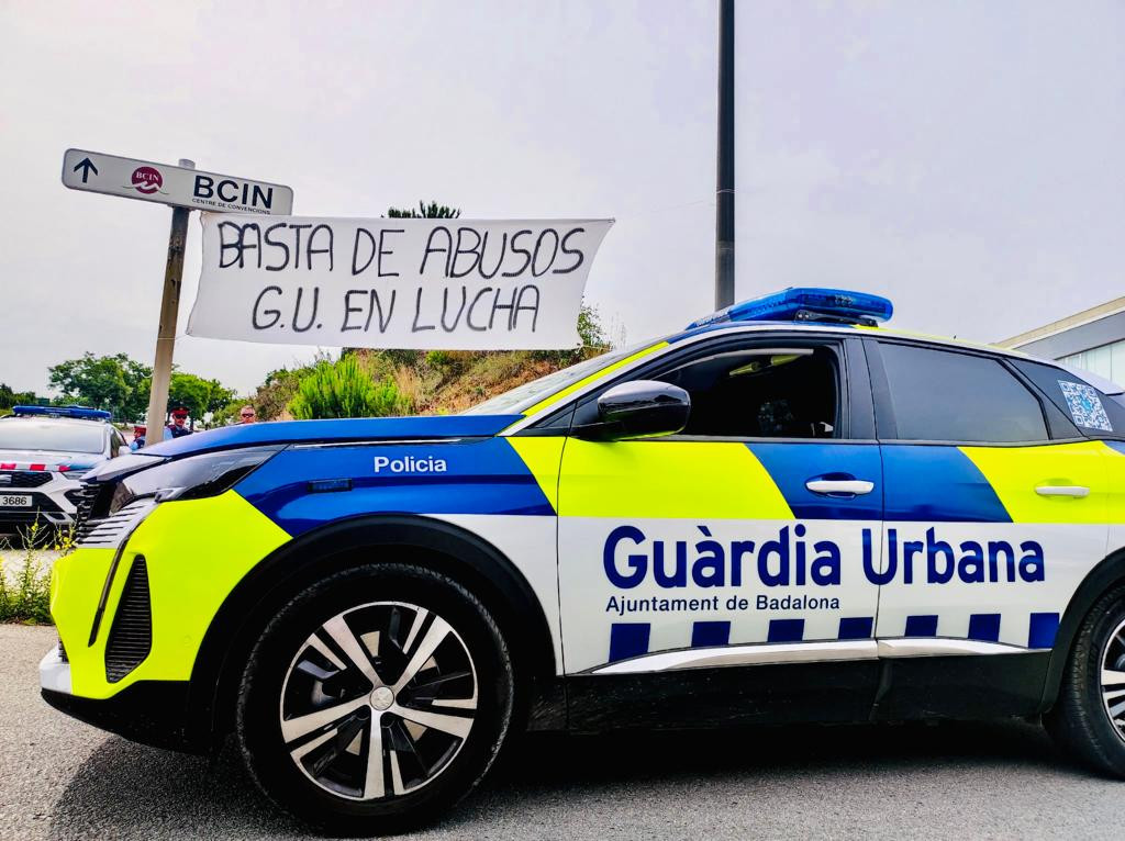 La pancarta de la manifestación con un coche de la Guardia Urbana al frente / CEDIDA