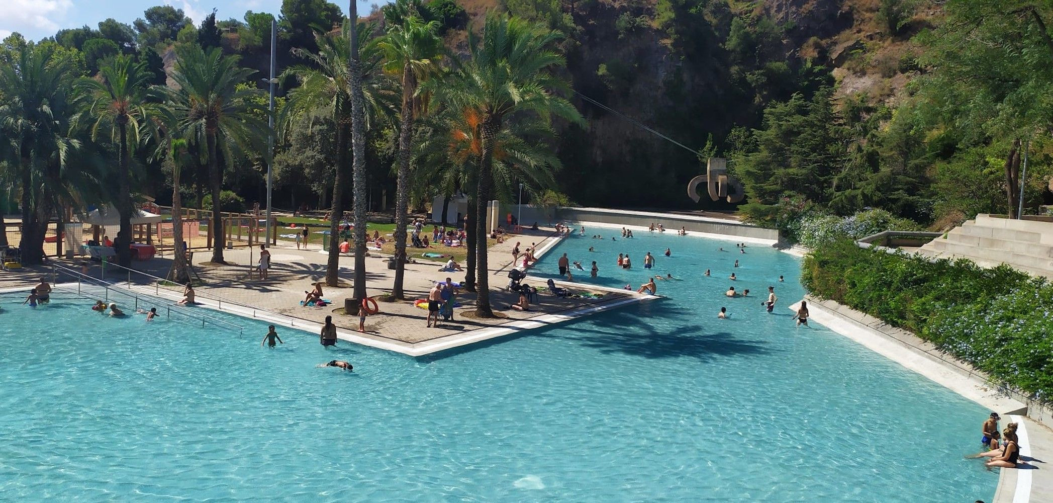 El lago de la Creueta del Coll, rodeado de palmeras y con la escultura de Chillida a la derecha / ERC