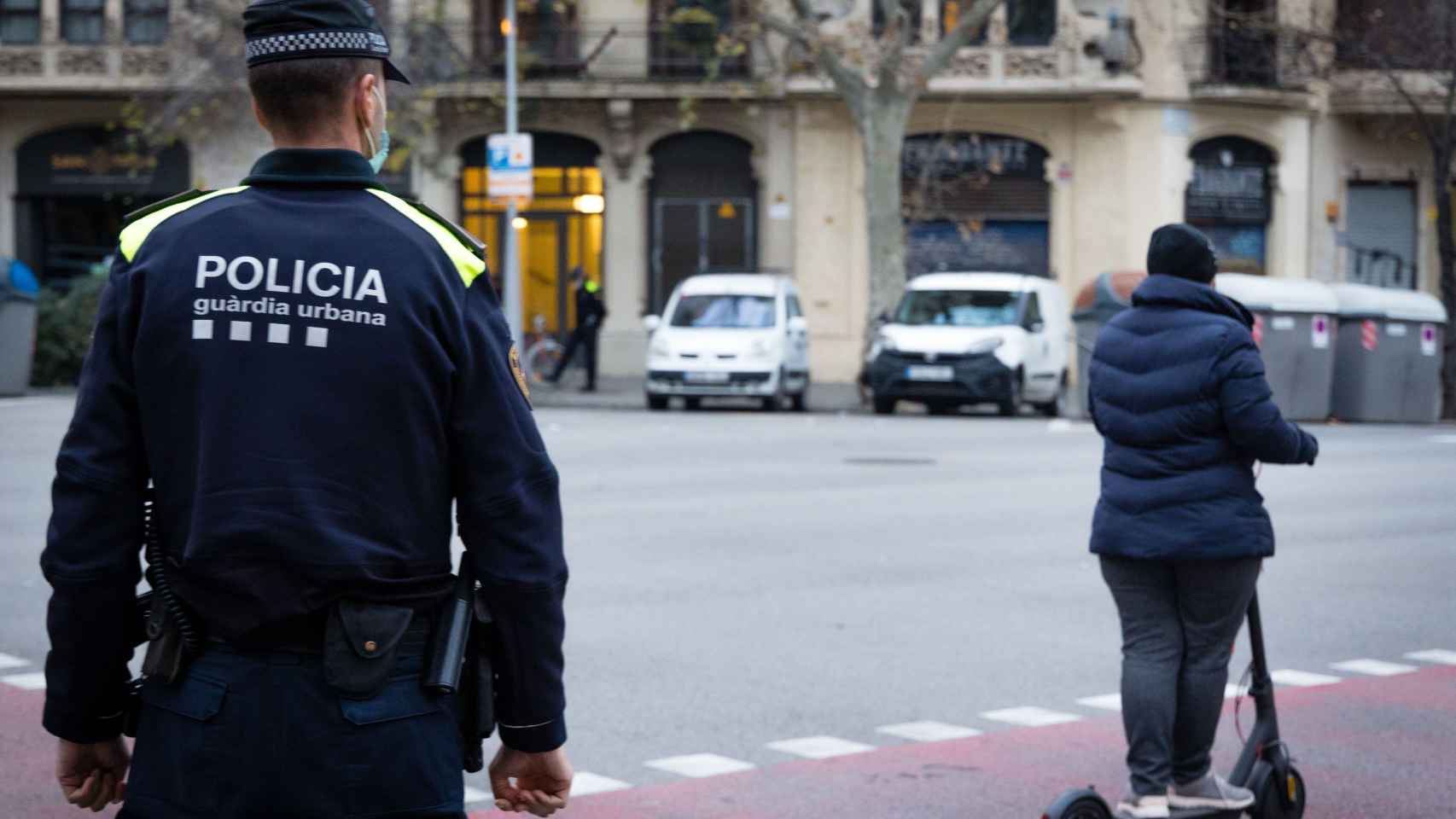 Un agente de la Guardia Urbana junto a un conductor de un patinete eléctrico